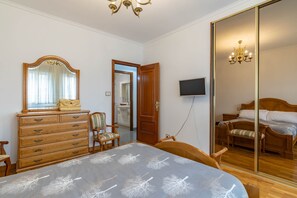 Une chambre à coucher avec un lit, une commode, une télévision et un miroir.