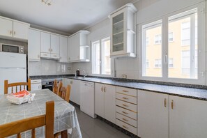 Une cuisine moderne avec des meubles blancs, un plan de travail en granit et un coin repas comprenant une table et des chaises.