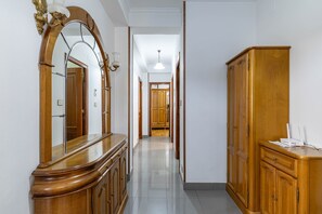 Un couloir avec des armoires en bois, un grand miroir et un luminaire au plafond.