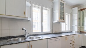 Una cocina con armarios blancos, un lavamanos doble y un lavavajillas.