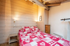 A wooden-paneled room with a bed, a small wooden nightstand, a radiator, and a wooden cabinet.