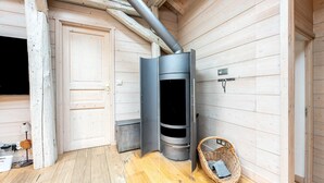 Un interior de madera con una chimenea moderna, una puerta y una cesta de mimbre.