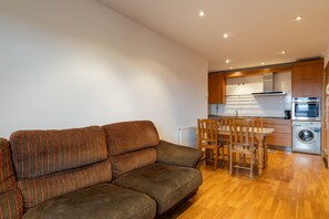 A modern living room with a sofa and a dining area with chairs and a table. - Celso Emilio Ferreiro Apartment in the Heart of Ribeira Sacra with Views of Monforte (Monforte de Lemos)