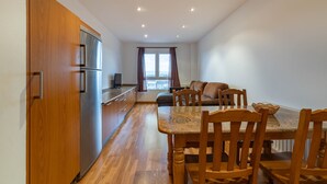 Una cocina moderna con armarios de madera y electrodomésticos de acero inoxidable, un comedor con mesa de granito y sillas de madera, y una sala de estar con sofá y un ventanal grande.