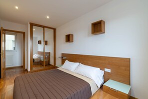 Une chambre à coucher avec une tête de lit en bois, un lit recouvert d’une couverture marron, une table de chevet et un miroir.