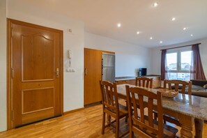 Une cuisine moderne avec des meubles en bois, un coin repas comprenant une table et des chaises, et une grande fenêtre avec des rideaux.