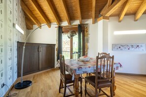 Un comedor con una mesa de madera, sillas, una lámpara de pie y vistas al exterior.