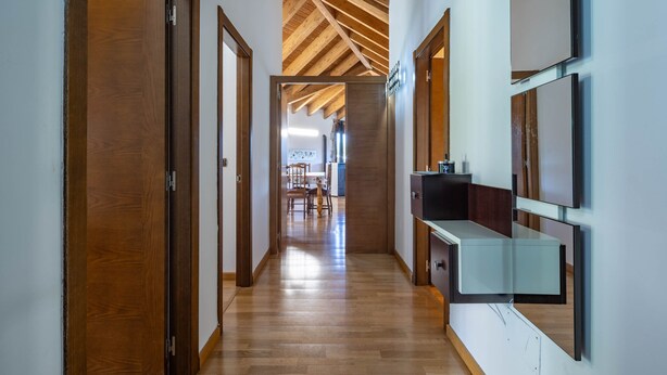 Een gang met houten deuren, een houten plafond en een moderne keuken met aanrecht en kasten.