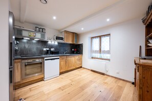 Een moderne keuken met roestvrijstalen apparatuur, houten kastjes en een groot raam.
