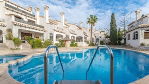 A swimming pool with a clear view of the surrounding architecture, including a building with multiple balconies and a palm tree.