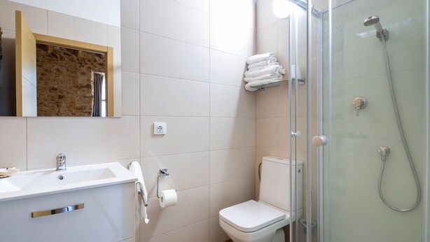 Ein Badezimmer mit weißem Waschbecken, Toilette und einer Duschkabine.