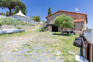 A stone building with a red roof, a staircase, and a covered area with a white canopy.