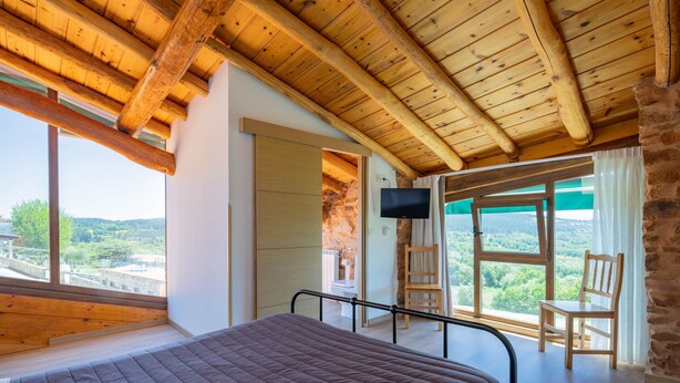 A bedroom with a wooden ceiling, a bed, a TV, and a view of the landscape. - Casa Tunino with Shared Pool, Terrace, and Wi-Fi (Monforte de Lemos)