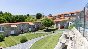 A stone building with a red-tiled roof, a stone pathway, and a small tree. - 'Baloco' Apartment with Shared Pool, Terrace, and Wi-Fi (Monforte de Lemos)