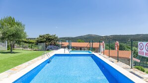 A rectangular swimming pool with a clear blue water surface, surrounded by a stone border and a metal fence. - 'Baloco' Apartment with Shared Pool, Terrace, and Wi-Fi (Monforte de Lemos)
