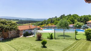 Une propriété résidentielle dotée d’une piscine, de murs en pierre et offrant une vue sur des collines lointaines.