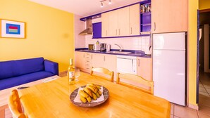 Una cocina compacta con una mesa de comedor, un sofá y un refrigerador.