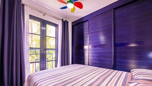 Habitación de hotel con cama, cortinas, ventana y ventilador de techo.