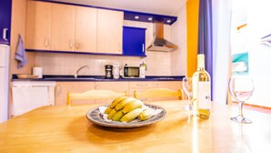 A kitchen with wooden cabinets, a microwave, a coffee maker, a plate of bananas, a wine bottle, and a wine glass on a table. - Apartment 'Nautilus 7' with Private Terrace and Wi-Fi (Puerto Naos)