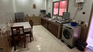 A compact kitchen with a dining area, a washing machine, and a microwave.