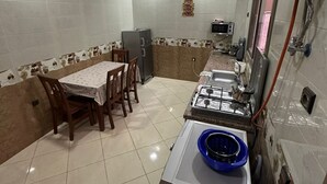 Una cocina compacta con una mesa, sillas, refrigerador, estufa y dispensador de agua.