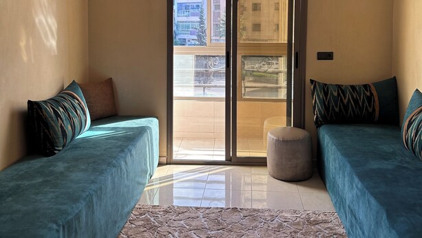 Una sala moderna con dos sofás, un tapete estampado, una araña y un ventanal corredero que da a un espacio exterior.