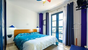 Un dormitorio con cama, ventana con cortinas, lámpara de pared y puerta.