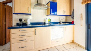 Una cocina con armarios de madera, encimera azul, campana de acero inoxidable y un fregadero.