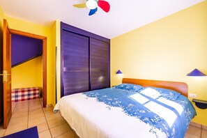 Ein Schlafzimmer mit Bett, Deckenventilator, Kleiderschrank, Nachttisch und Lampe.