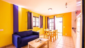 Una sala de estar con un sofá, una mesa de comedor y sillas.