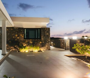 Eine moderne Außenpatio mit Steinmauern, einer flachen Dachkonstruktion und Blick zum Himmel.
