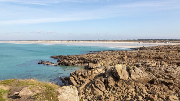 Un paysage côtier caractérisé par un terrain rocheux et une plage.