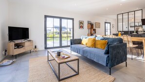 Un salon moderne comprenant un canapé, une table basse, un téléviseur et un coin repas avec des chaises et une table.