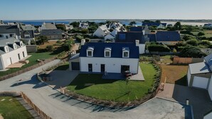 Un quartier résidentiel avec des maisons, une pelouse bien entretenue et une vue dégagée sur la mer.