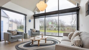 Un salon spacieux avec une grande fenêtre, un canapé, une table basse et un tapis.