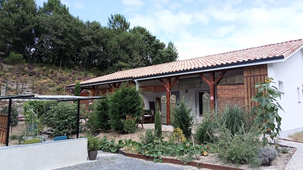 A house with a tiled roof, wooden beams, and a garden with various plants.