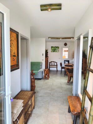 Un pasillo amplio con un sofá, bancos de madera y un comedor con sillas y una mesa.