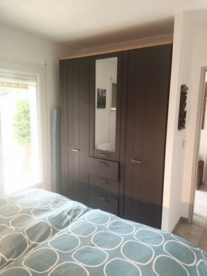 A bedroom with a bed, a wardrobe, and a window.