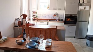 A kitchen with a wooden dining table, a refrigerator, and a window.