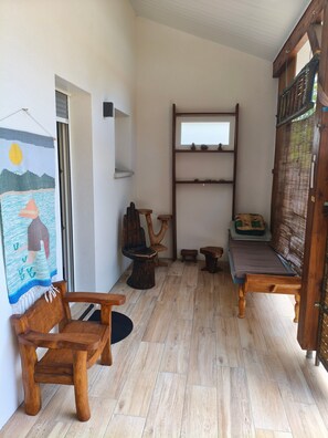 Una habitación pequeña y acogedora con piso de madera, una cama, una silla, una mesita y un estante en la pared.