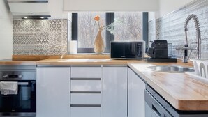 A modern kitchen with a microwave, coffee maker, and a window with a vase.