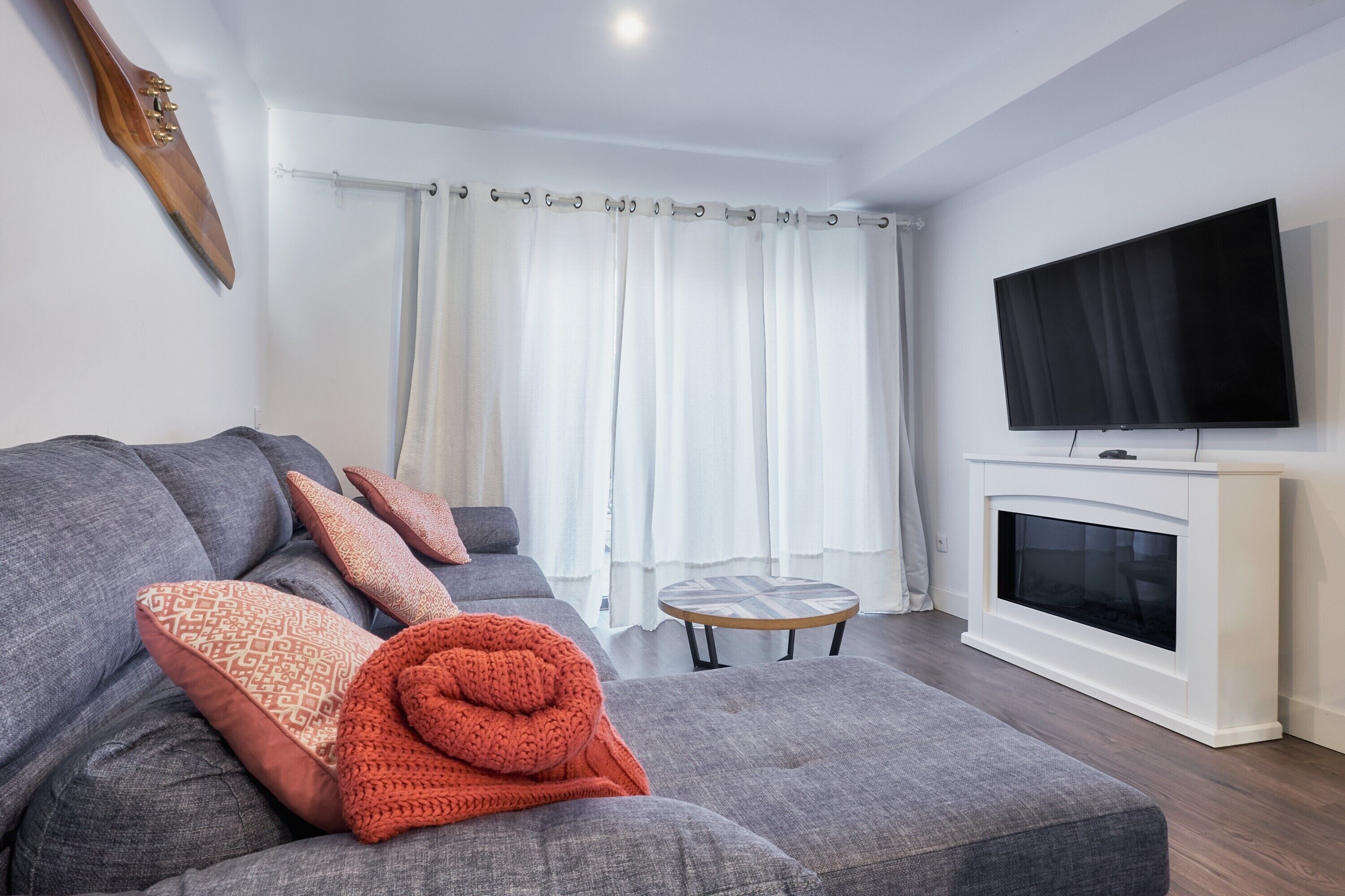 A modern living room with a grey sofa, a television, and a fireplace.
