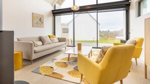 Una sala de estar moderna con un sofá, un sillón amarillo y una mesa de centro.
