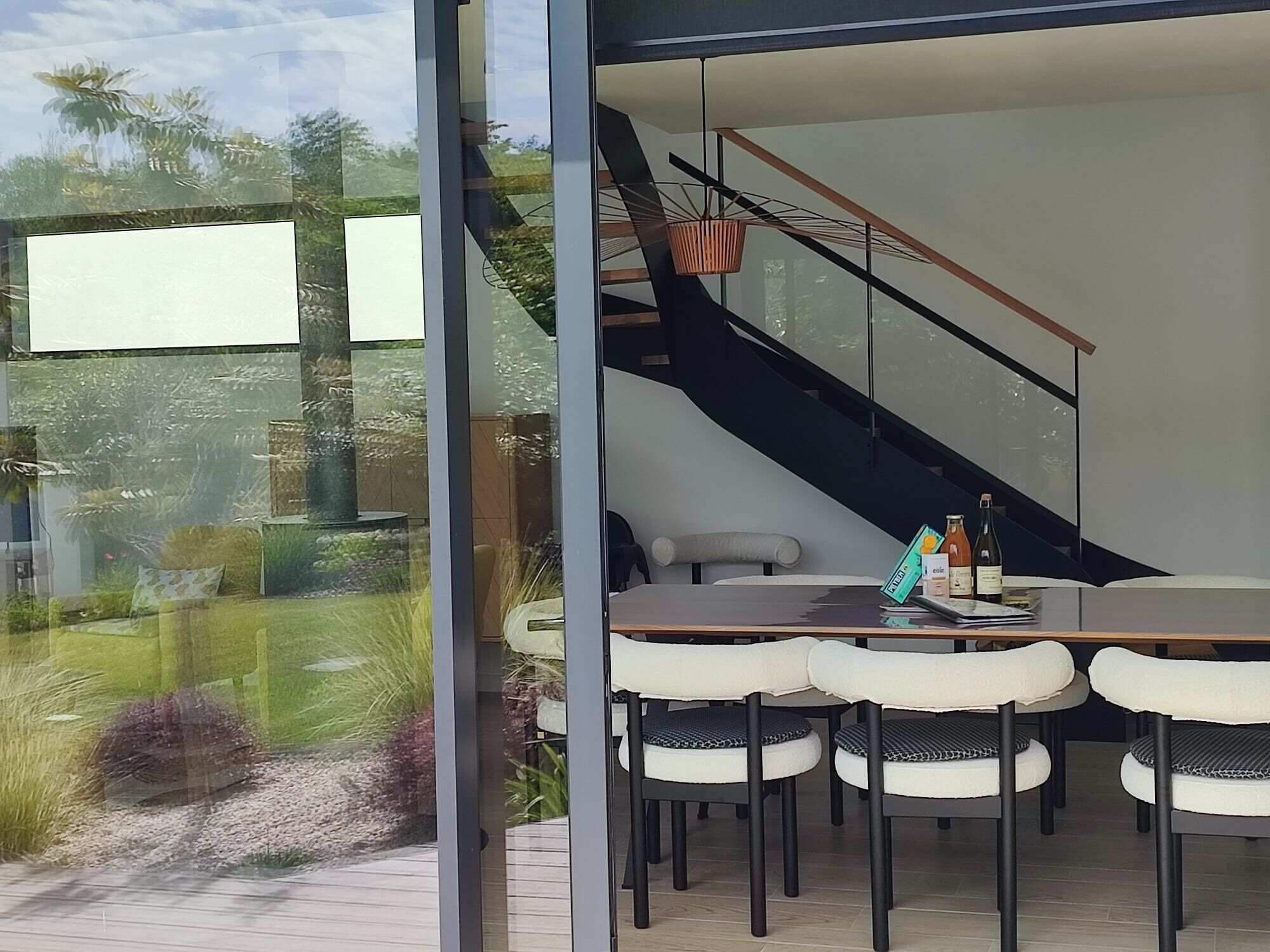 Un intérieur moderne comprenant un coin repas, un escalier et une vue sur l’extérieur.