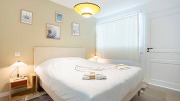 Ein Hotelzimmer mit einem Bett, Nachttischlampen, einer Tür und gerahmten Bildern an der Wand.