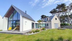 Una casa moderna con un gran ventanal, un edificio de piedra y un patio cubierto de césped.
