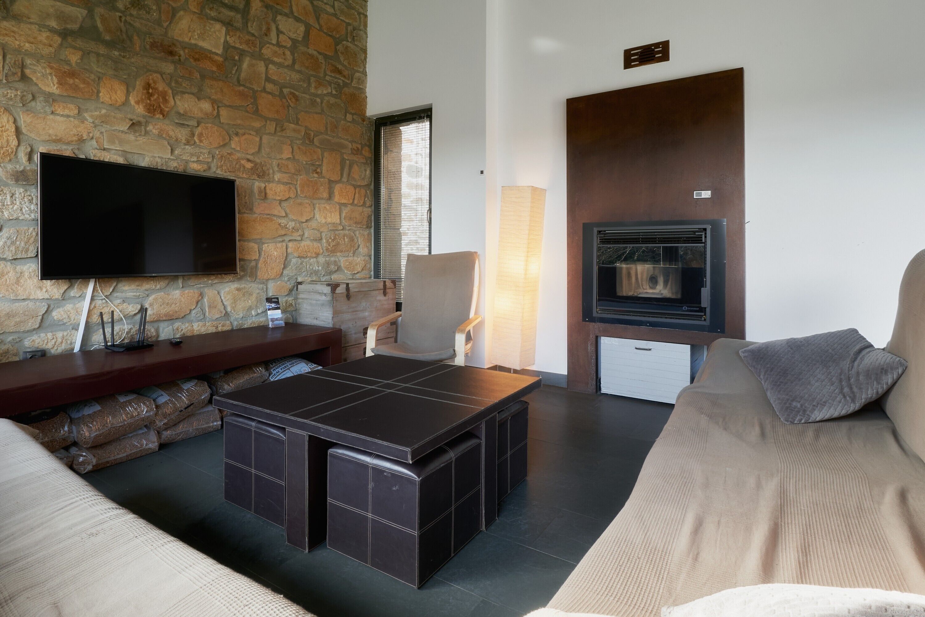 Una sala de estar moderna con una pared de piedra, un televisor de pantalla plana, una chimenea, un sofá y una mesa de centro.