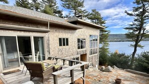 Une maison avec une terrasse, du mobilier d’extérieur et une vue sur un lac.