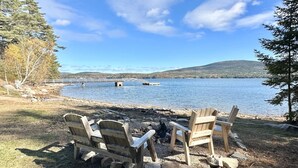 Un cadre idyllique au bord du lac, avec un foyer et des fauteuils Adirondack.