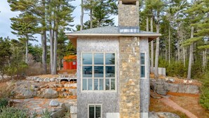 Une maison en pierre avec une cheminée, de grandes fenêtres et des fondations en pierre.